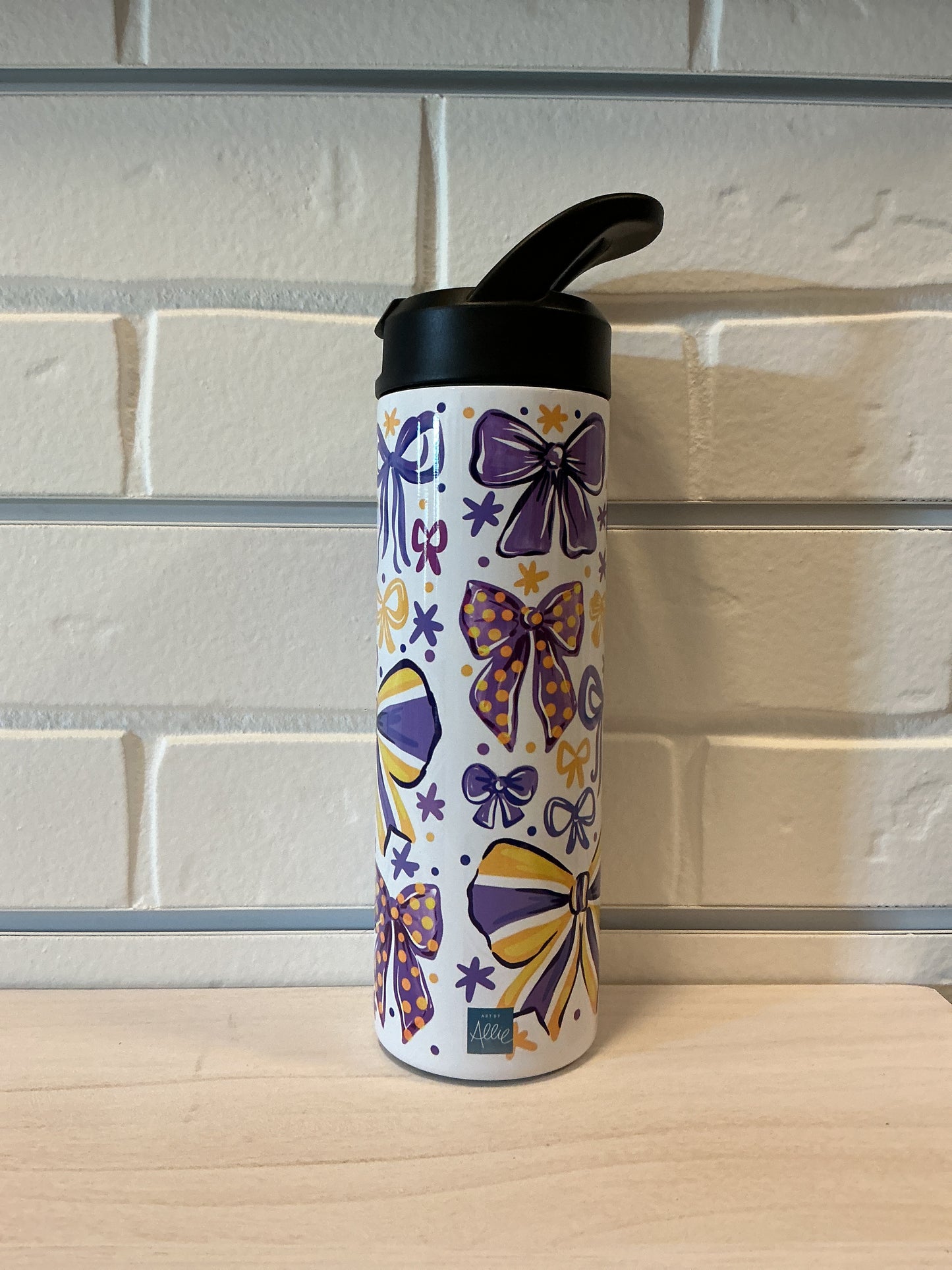 Colorful water bottle with purple and yellow designs on a glass surface