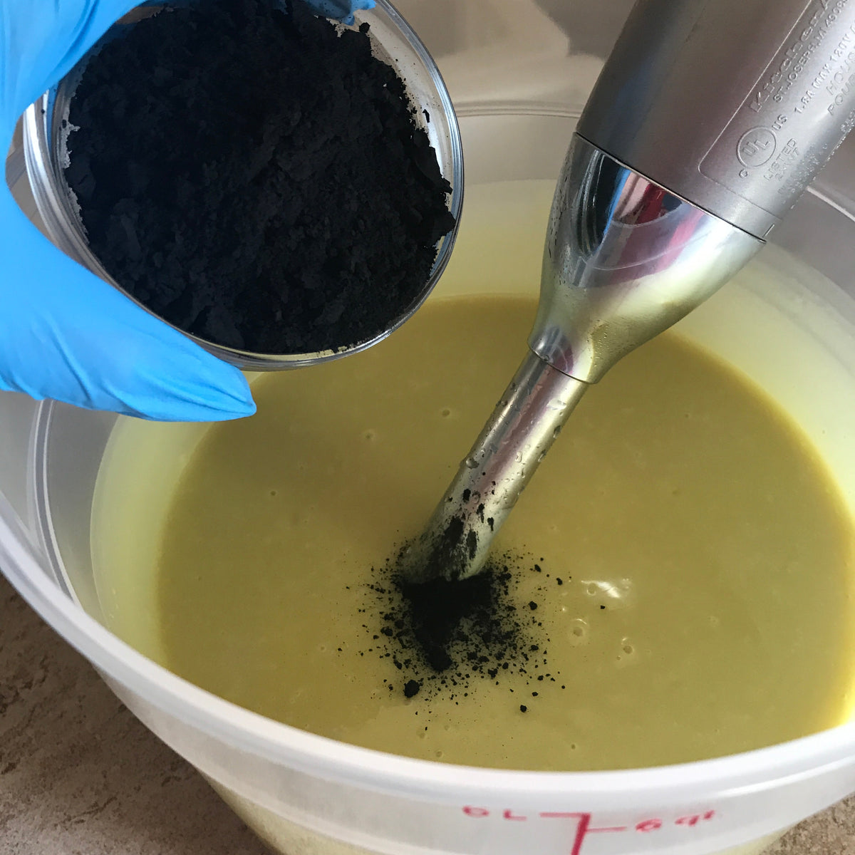 Charcoal being stirred into soap oils during soap making