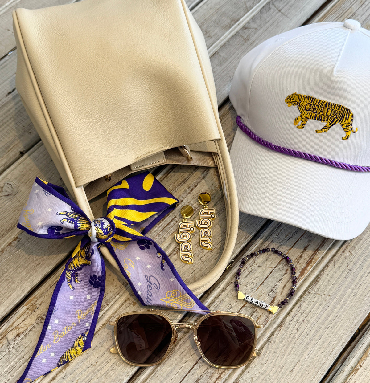 Purple and gold silk twilly tied on a cream handbag with game day accessories