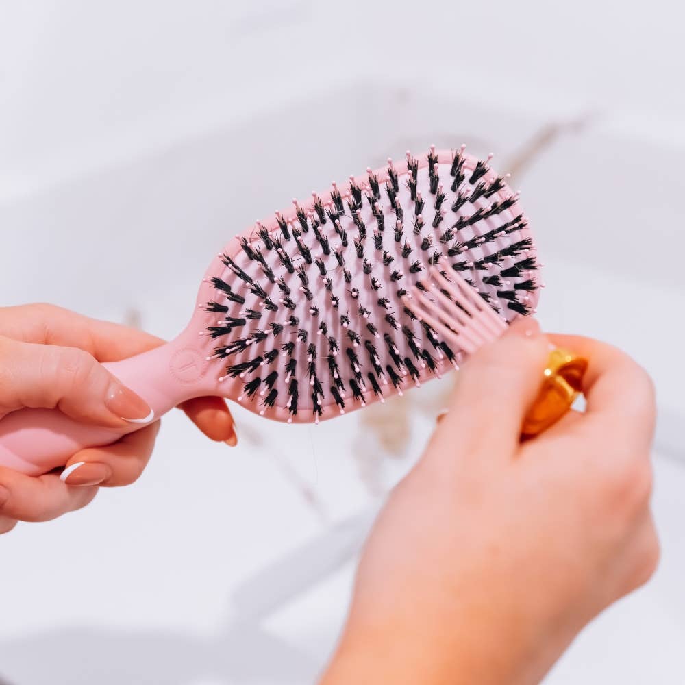 Hands removing the cleaner from the TELETIES boar bristle brush