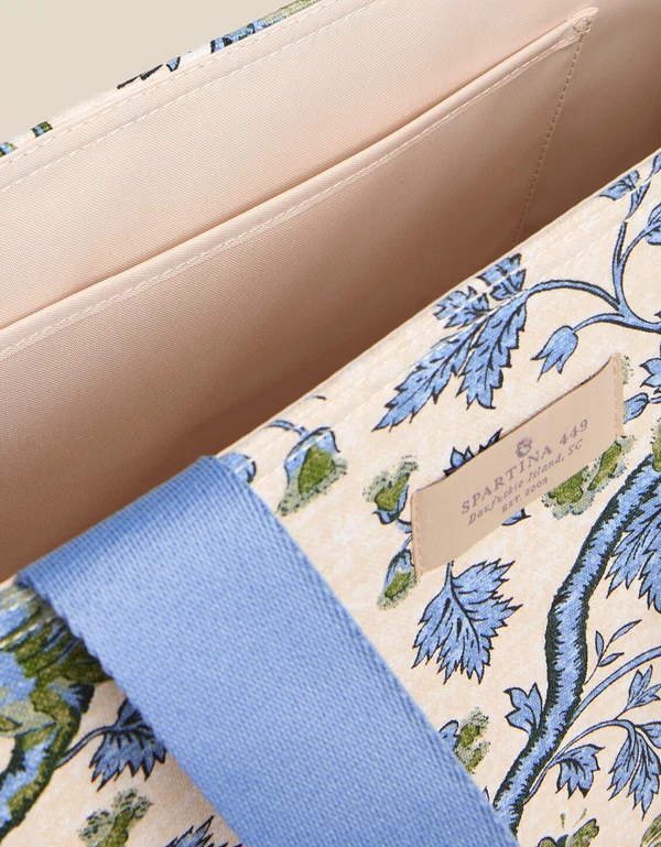 Close-up of a handbag interior and exterior corner showing a beige interior lining, a blue floral printed fabric exterior, and a light blue strap. A small leather brand tag reads SPARTINA 440.