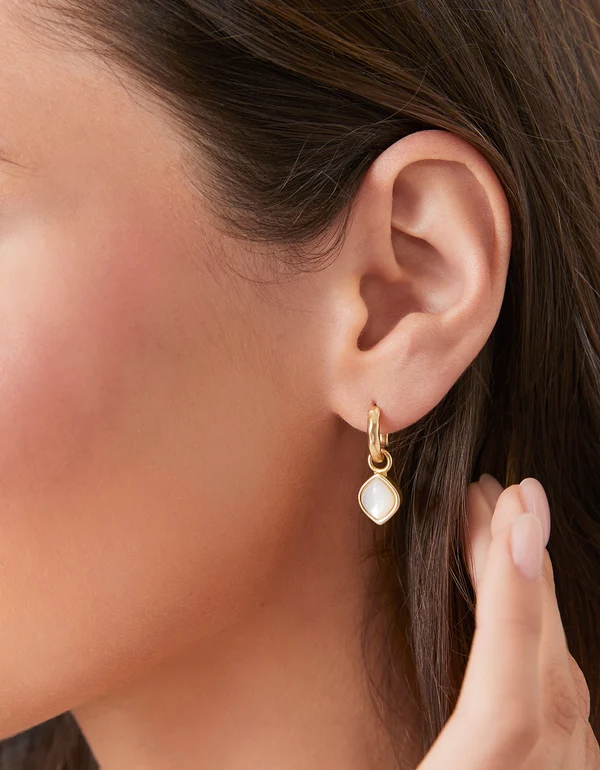 Close up of a model wearing drop hoop earrings with pearl.