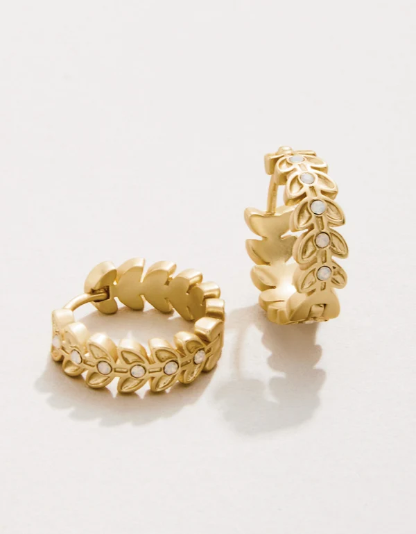 Gold hoop earrings with leaf design on a white background
