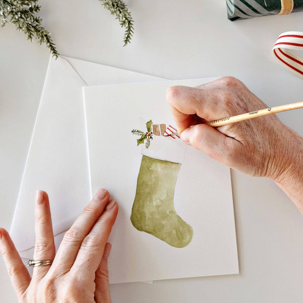 Painting a green stocking on a Christmas notecard