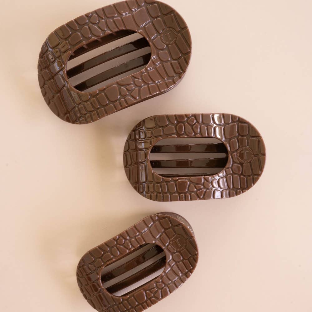 Three brown crocodile flat round hair clips on a neutral background