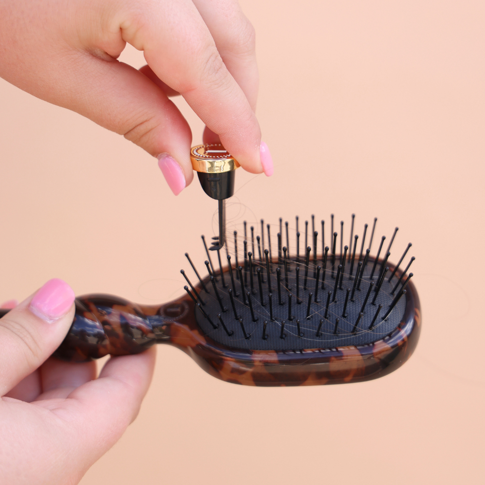 Hands removing the cleaner from the TELETIES mini detangler brush