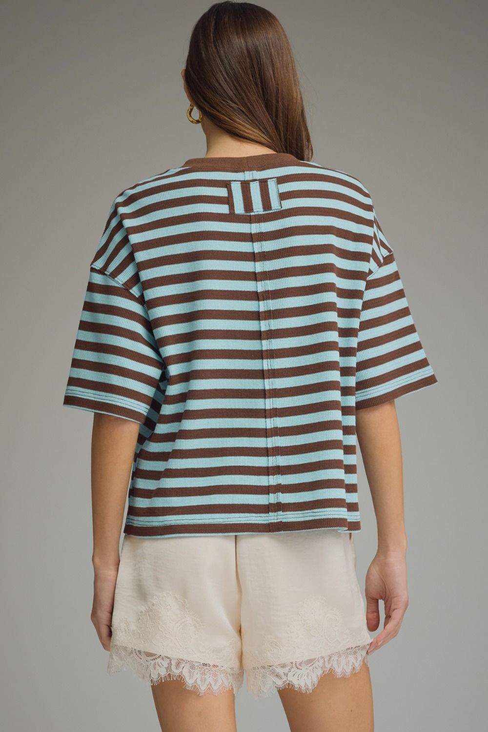 Person wearing a striped shirt and shorts on a plain background