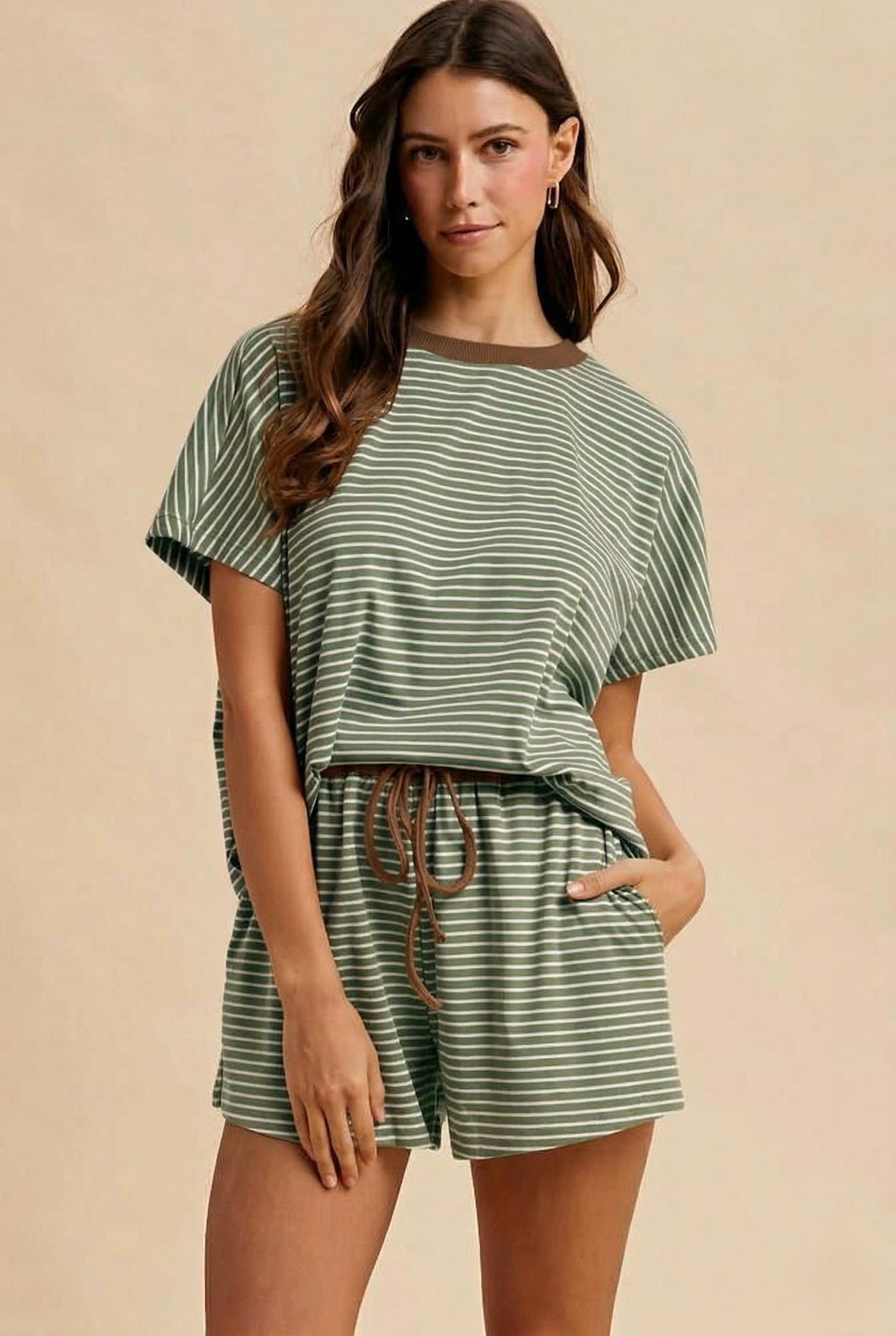 Woman wearing a green and white striped shorts set with brown accents on a beige background