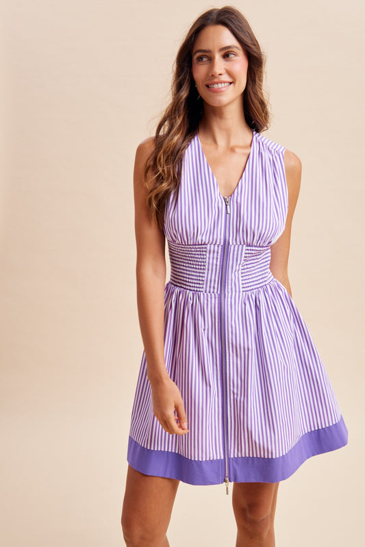 Woman wearing a purple and white striped dress against a beige background