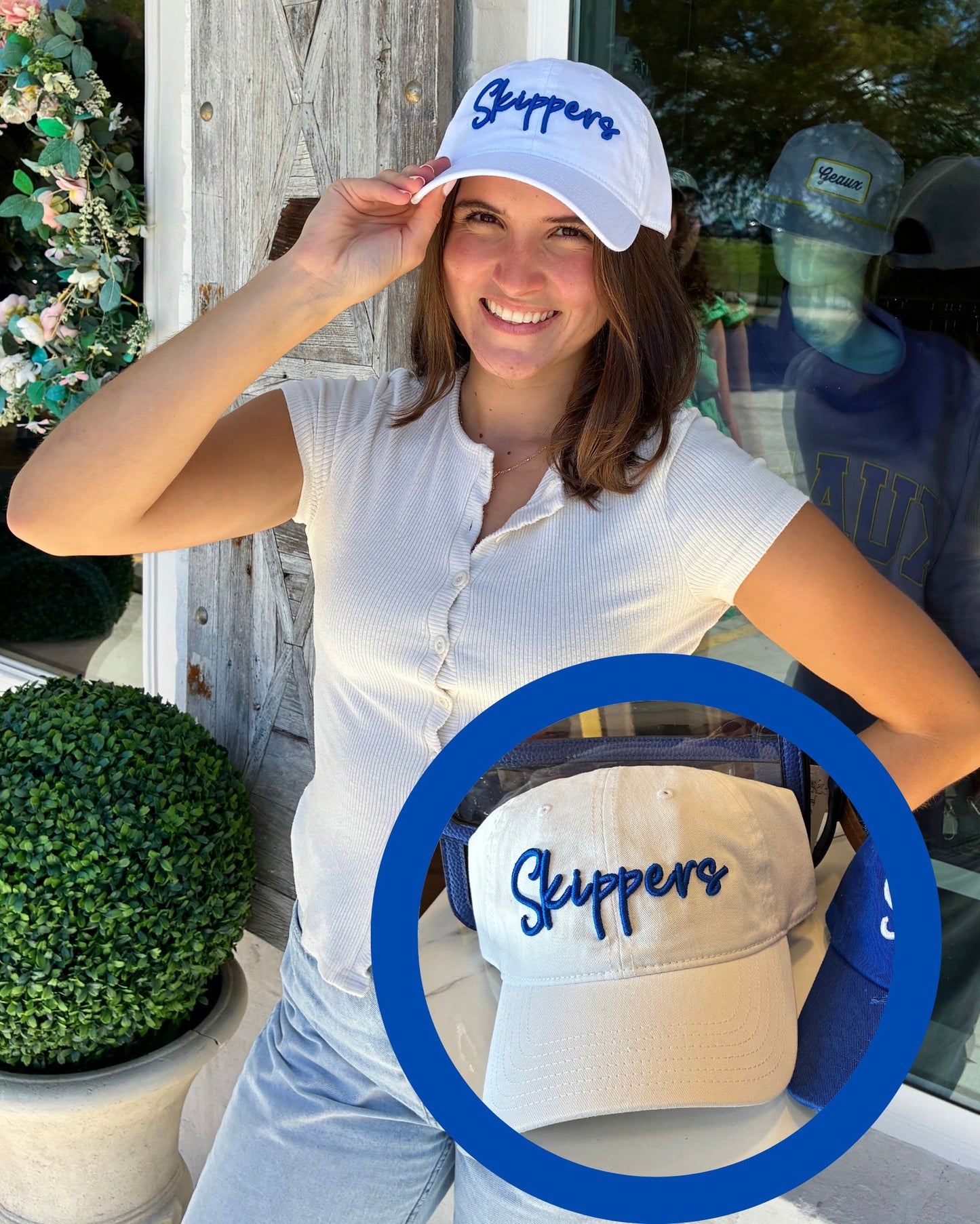A woman wearing a white baseball cap with blue 'Skippers' embroidery, posing in front of a rustic wooden door. A blue circular graphic overlay highlights the cap.