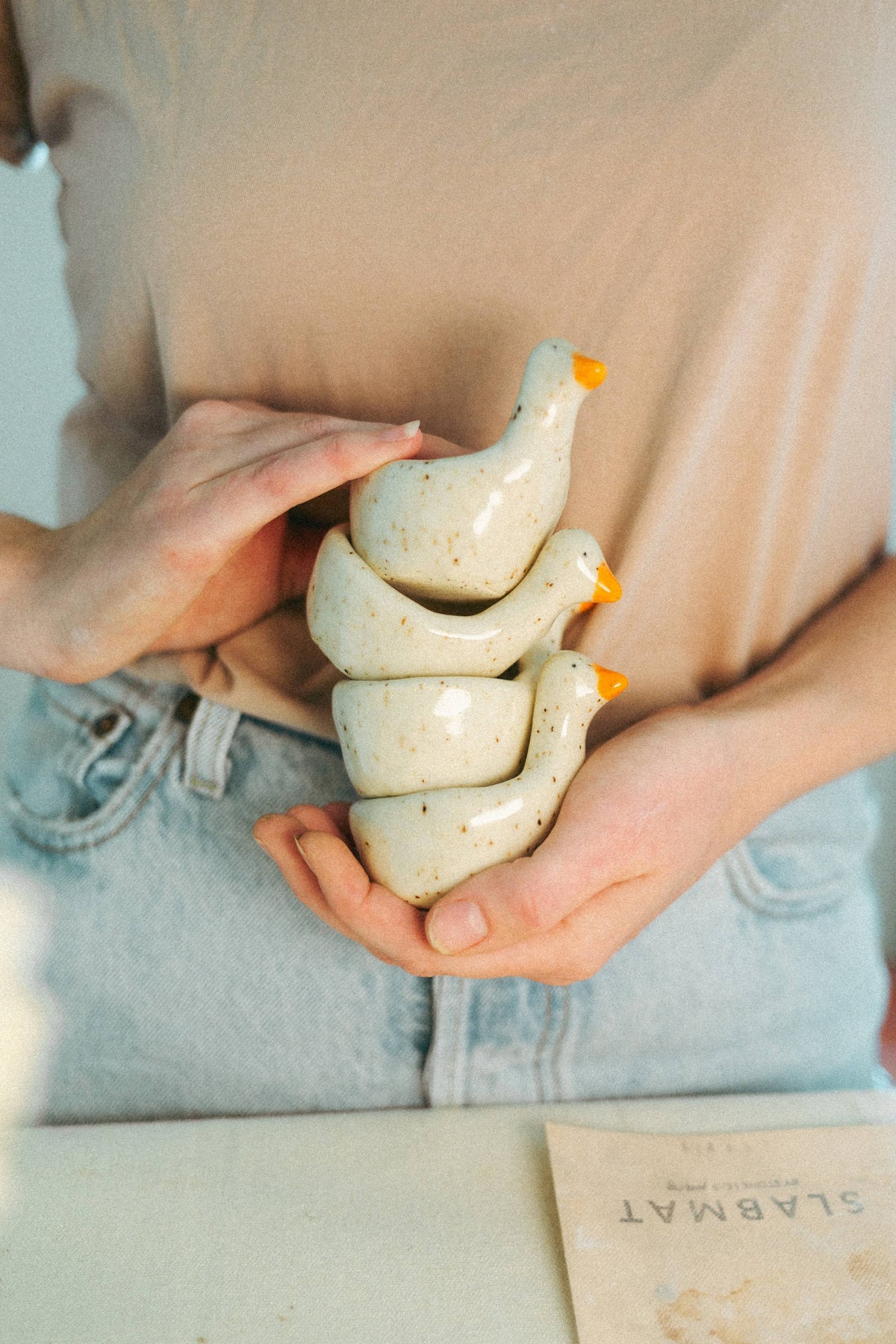 Hands holding a stack of four speckled ceramic goose ring dishes