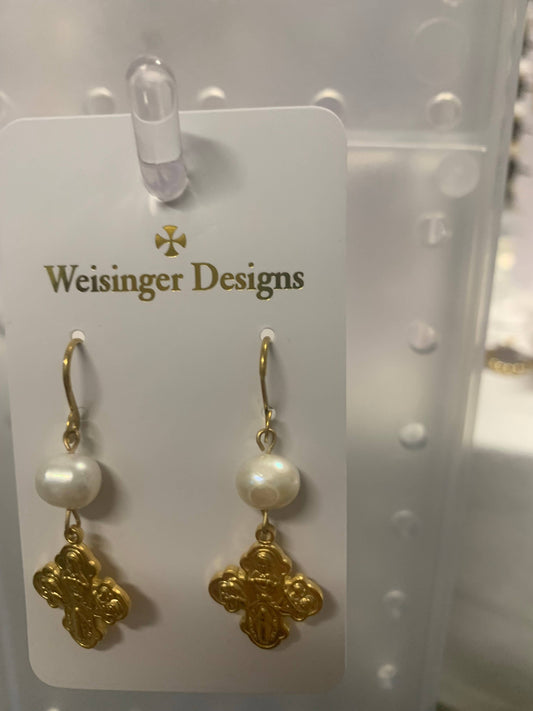 A pair of gold and pearl drop earrings by Weisinger Designs, featuring a round white pearl, a gold hook, and an ornate gold cross charm, displayed on a white card.