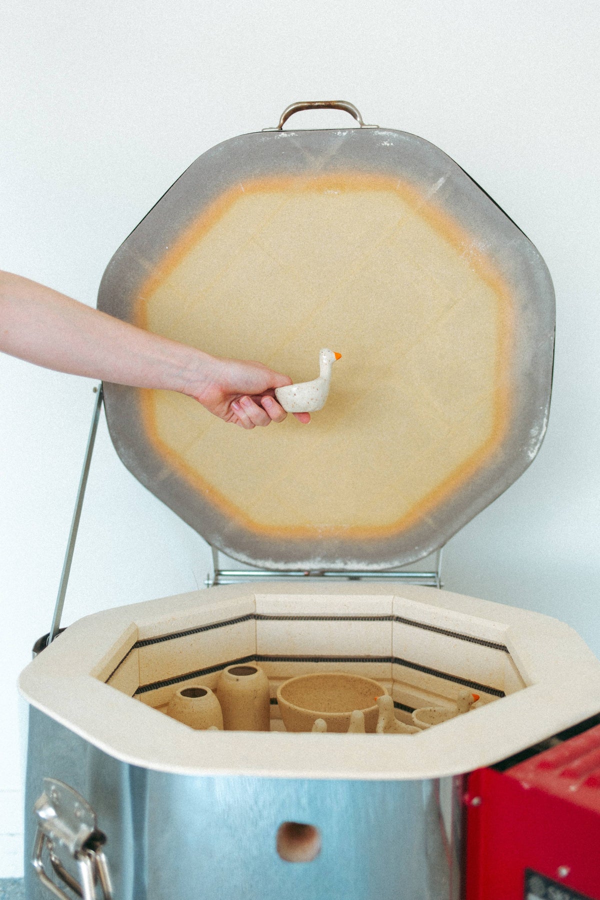 Artist placing a goose ring dish into an open pottery kiln