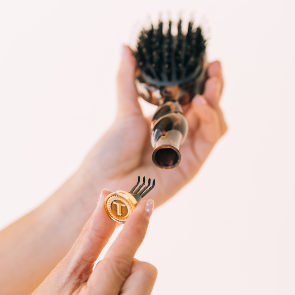 Hands removing the cleaner from the TELETIES mini boar bristle brush