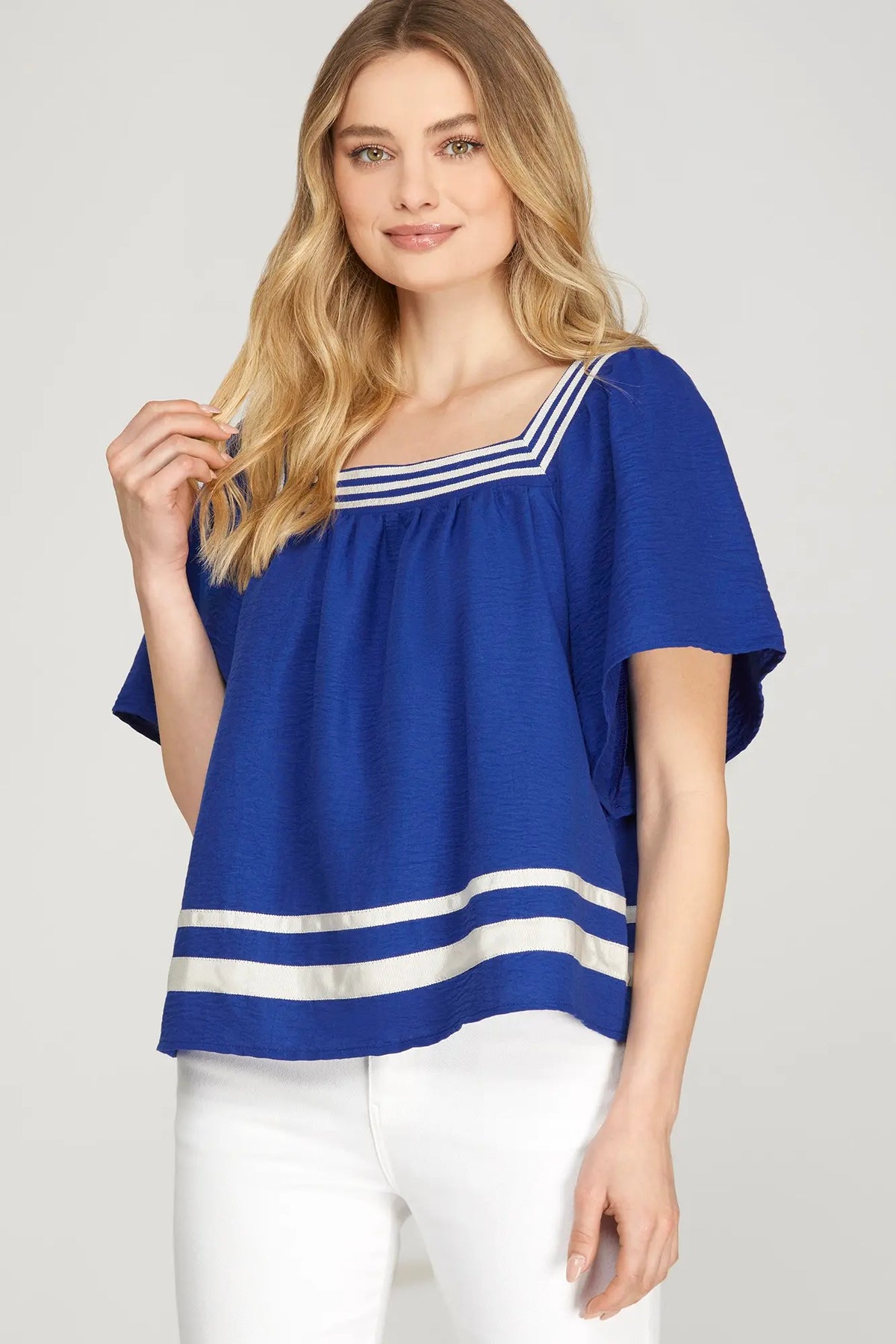 a women in a square neck royal Bule baby doll top with a white border around neck line and bottom