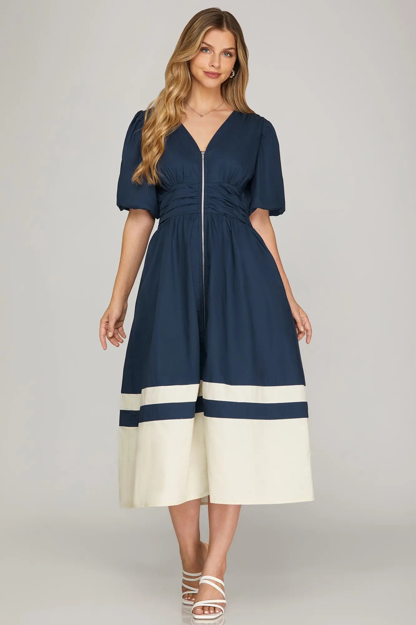Woman wearing a navy and white dress on a gray background