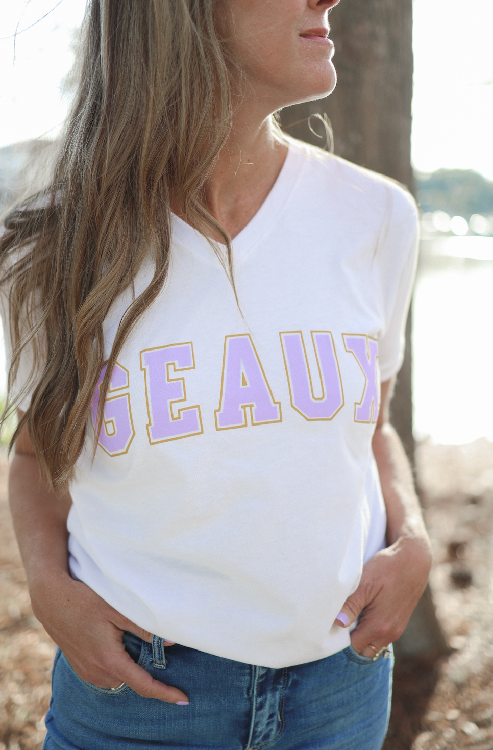 Person wearing a white t-shirt with 'GEAUX' printed on it, standing outdoors.