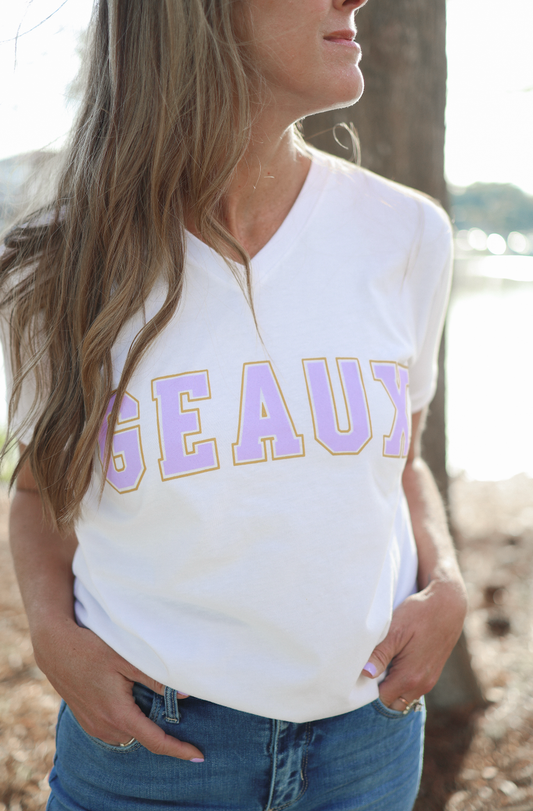 Person wearing a white t-shirt with 'GEAUX' printed on it, standing outdoors.