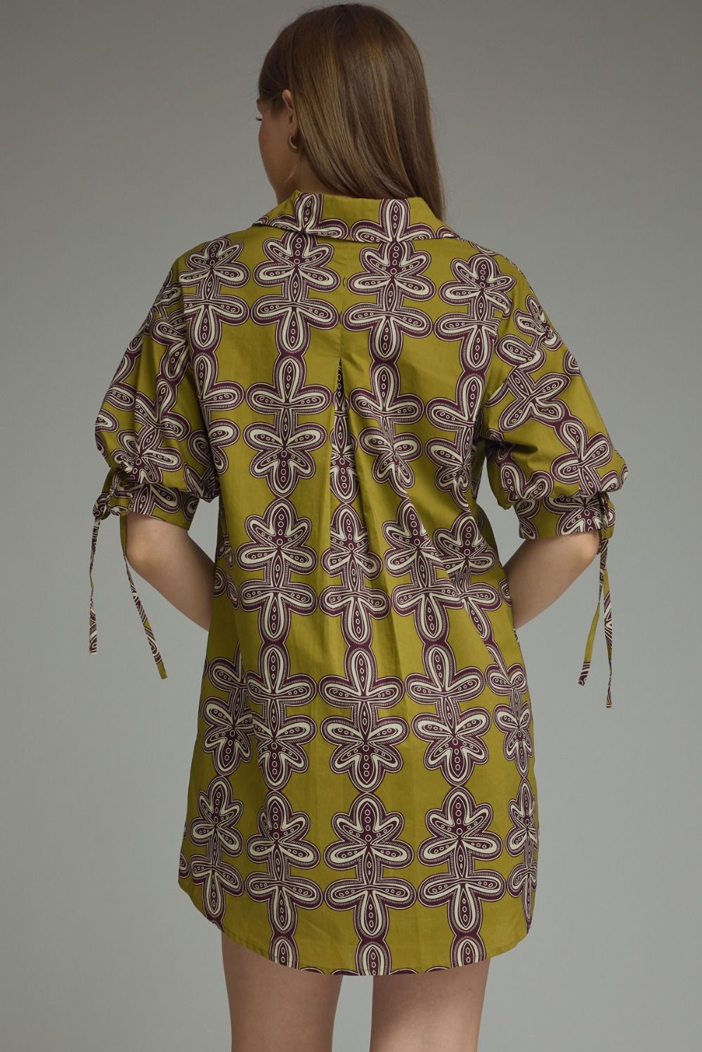 Woman wearing a patterned dress with a plain background
