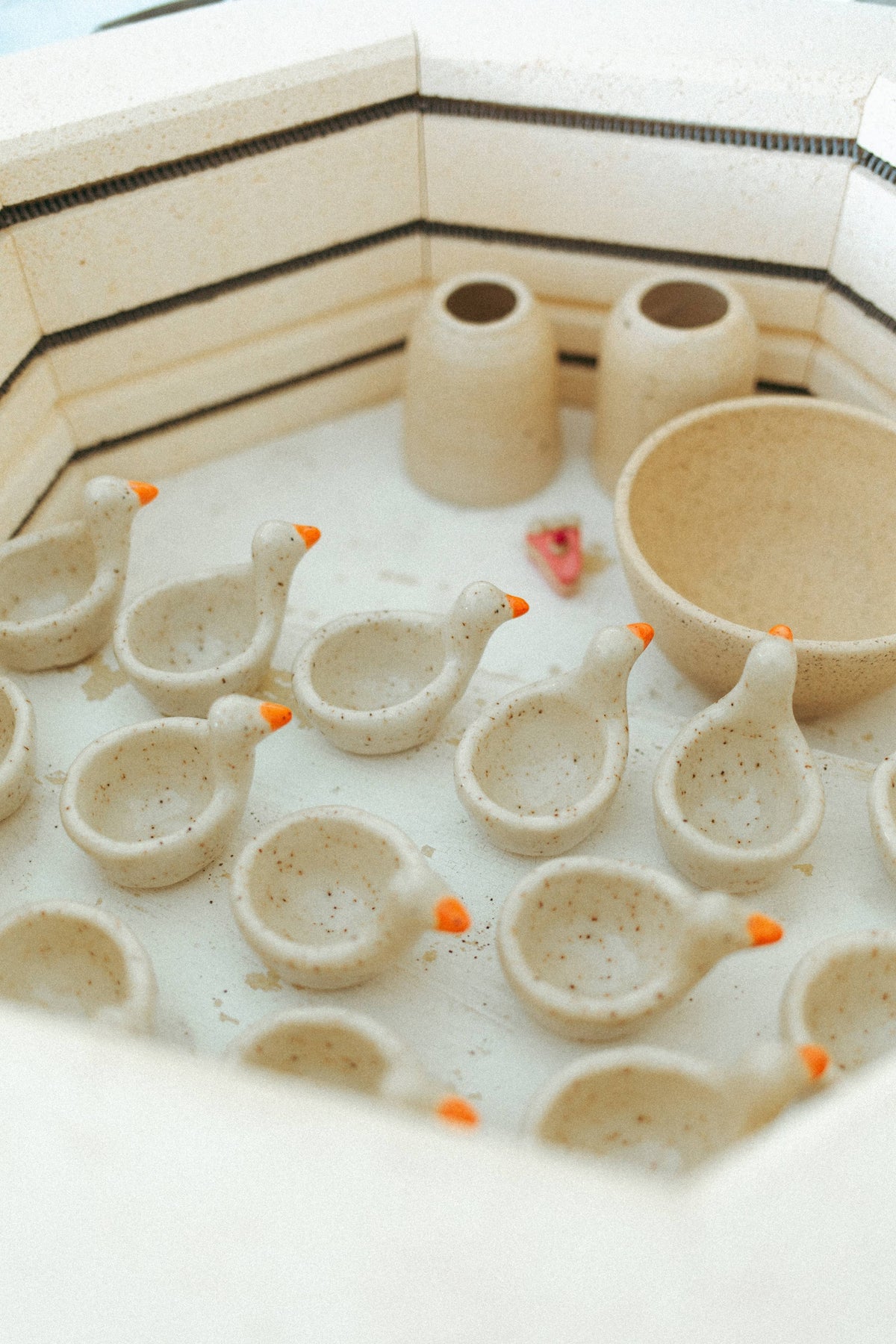 Rows of handmade ceramic goose ring dishes inside a pottery kiln