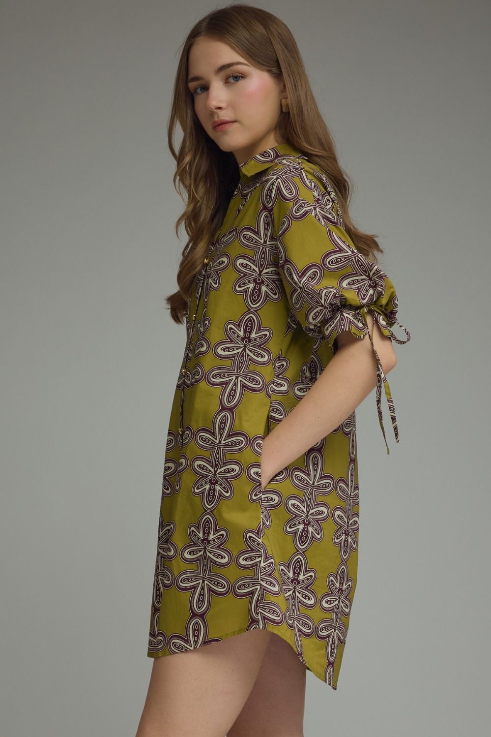 Woman wearing a green patterned dress against a gray background