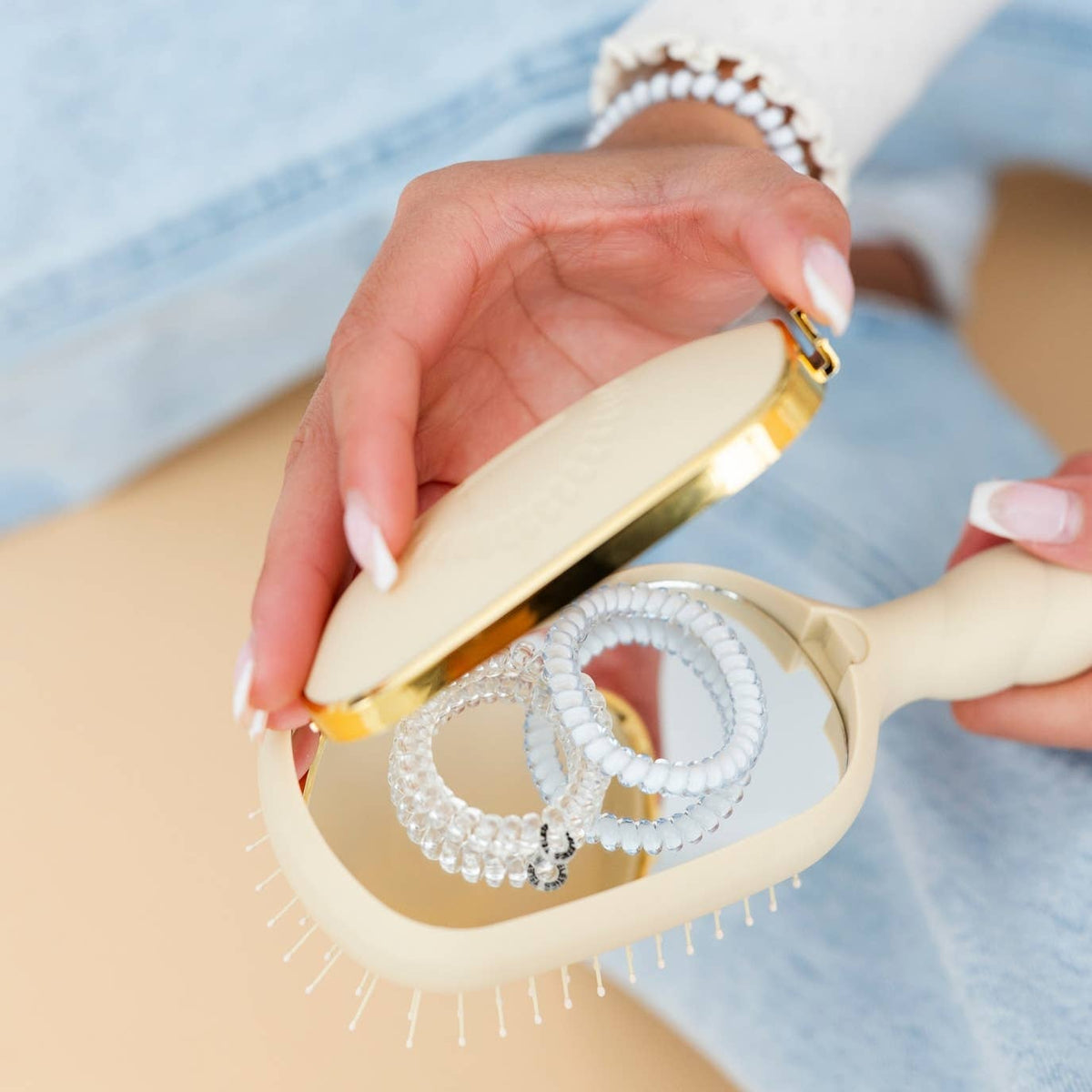 Hands removing the cleaner from the TELETIES detangler brush for medium hair