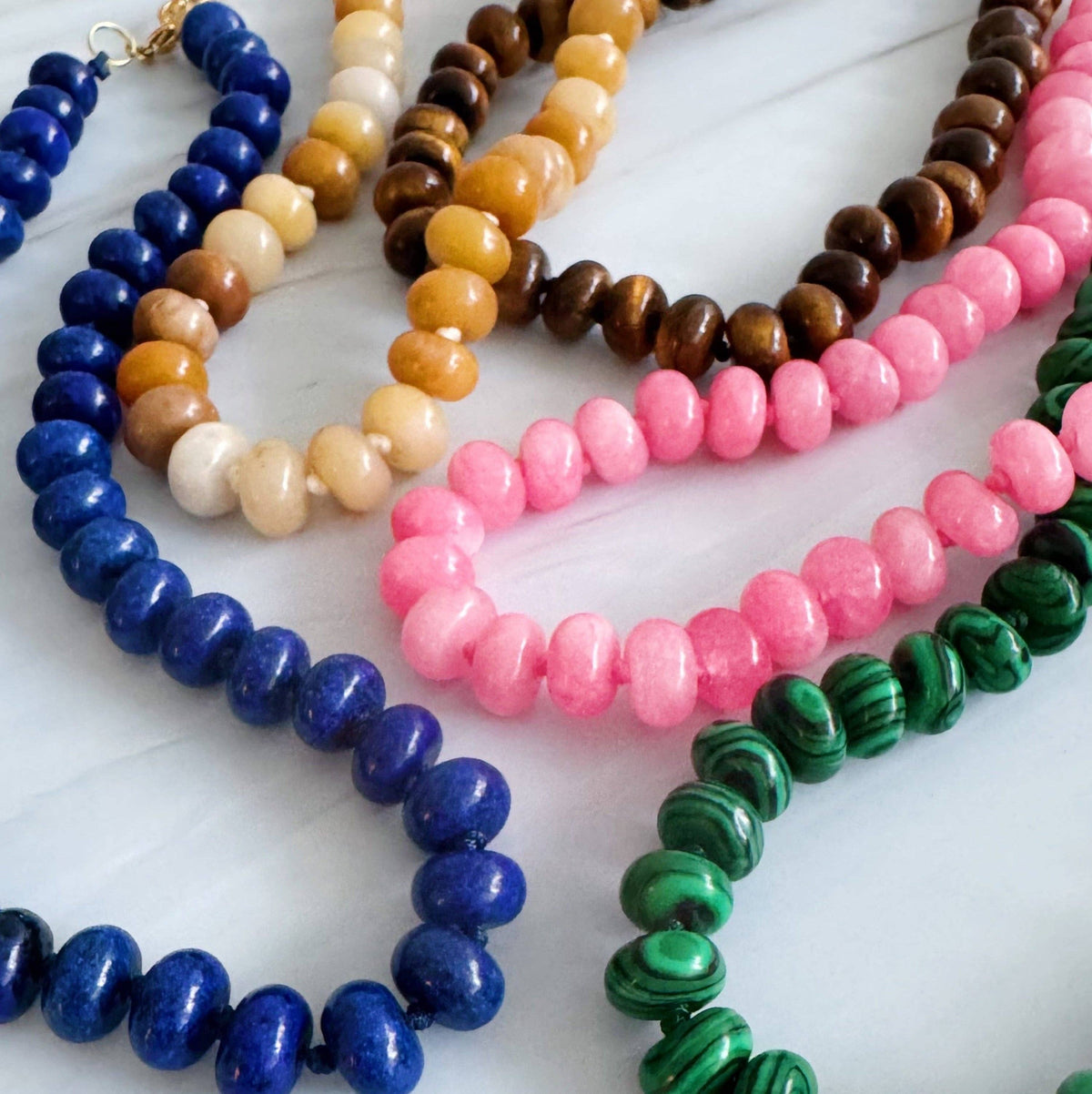 Colorful beaded necklaces on a white surface