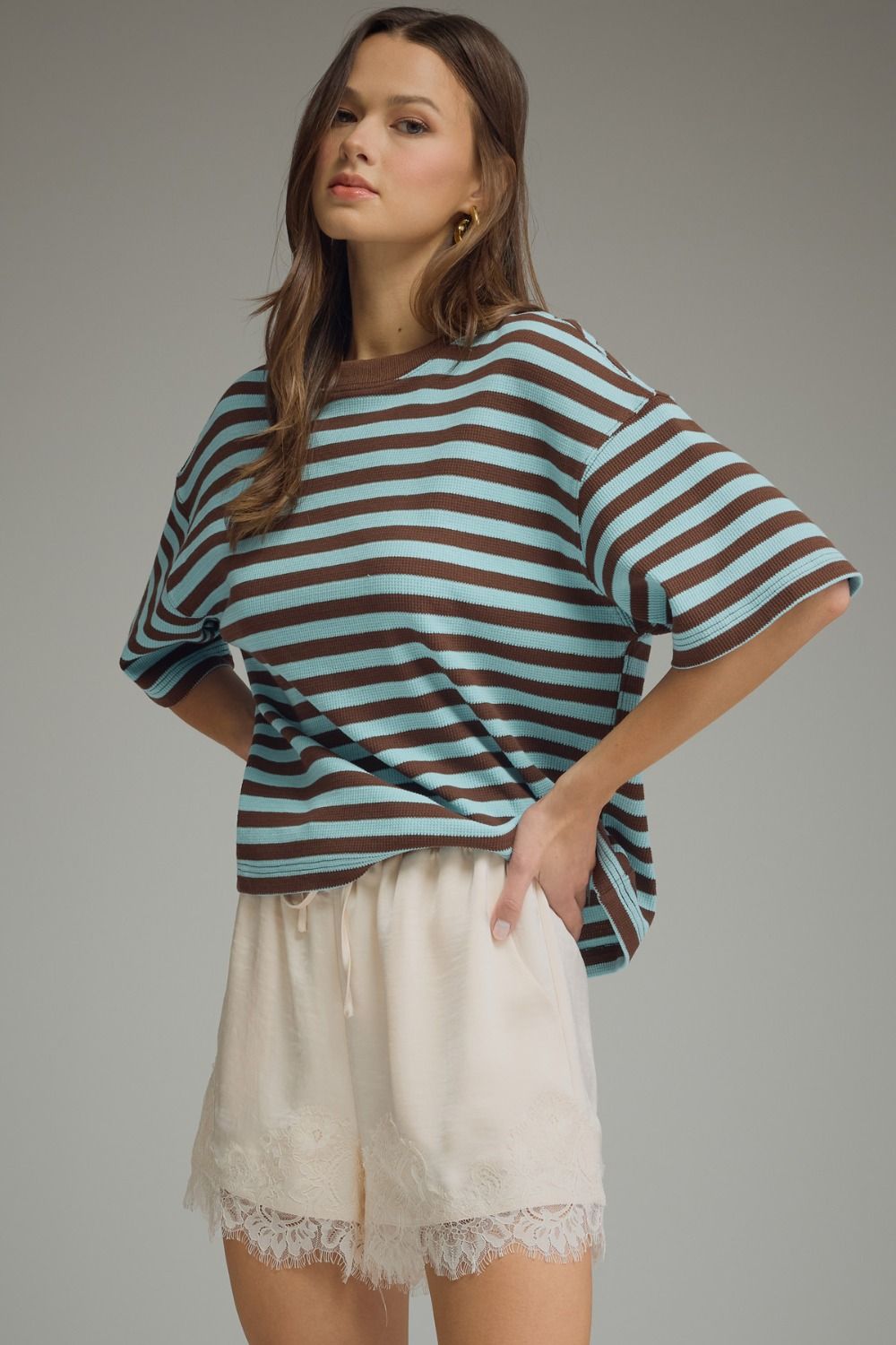 Woman wearing a striped shirt and shorts on a gray background