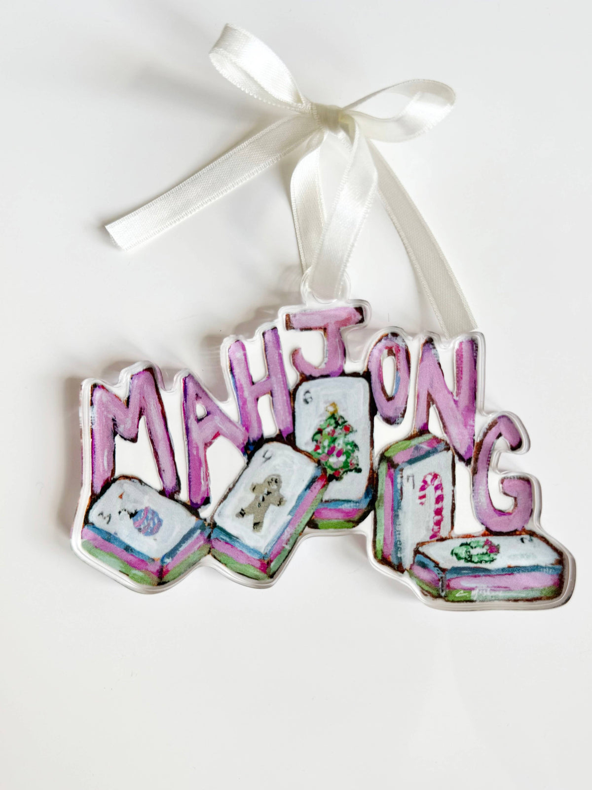Clear acrylic Mahjong Christmas ornament with pink letters and holiday tiles on a white ribbon