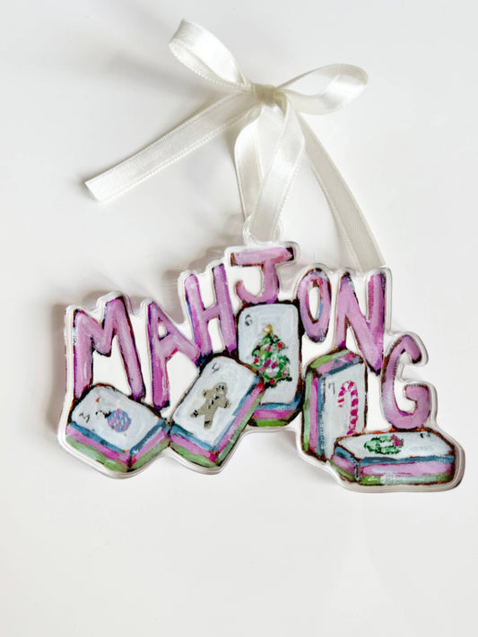 Clear acrylic Mahjong Christmas ornament with pink letters and holiday tiles on a white ribbon