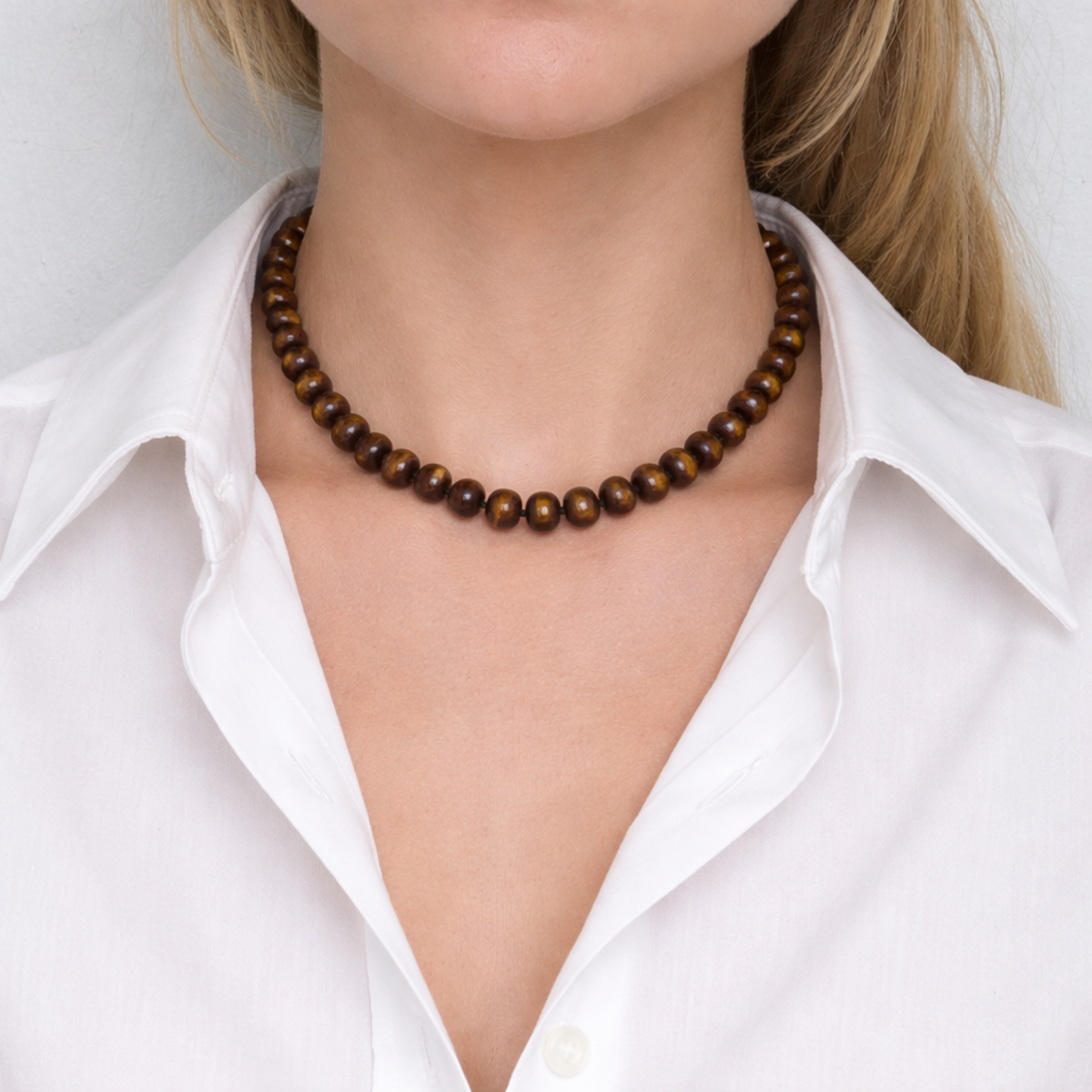 Brown beaded necklace worn by a person in a white shirt