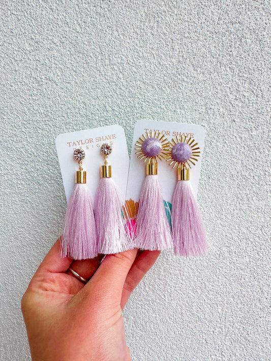 Purple tassel earrings on display against a neutral background