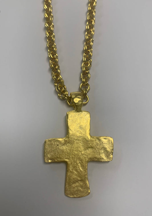 Gold cross pendant on a chain against a gray background