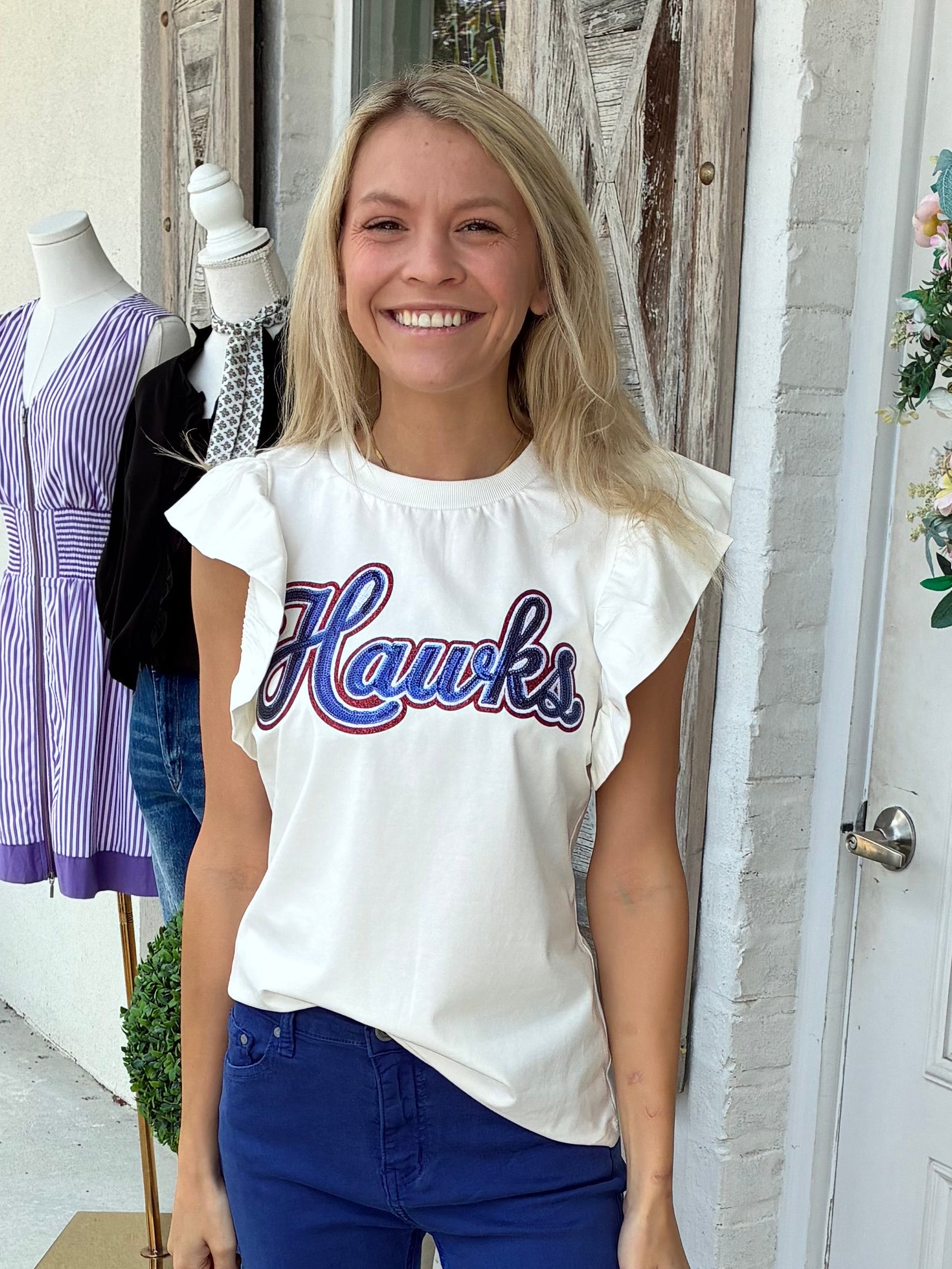 Hawks spirit sequin patch white flutter sleeve tee paired with blue pants and silver sneakers. 