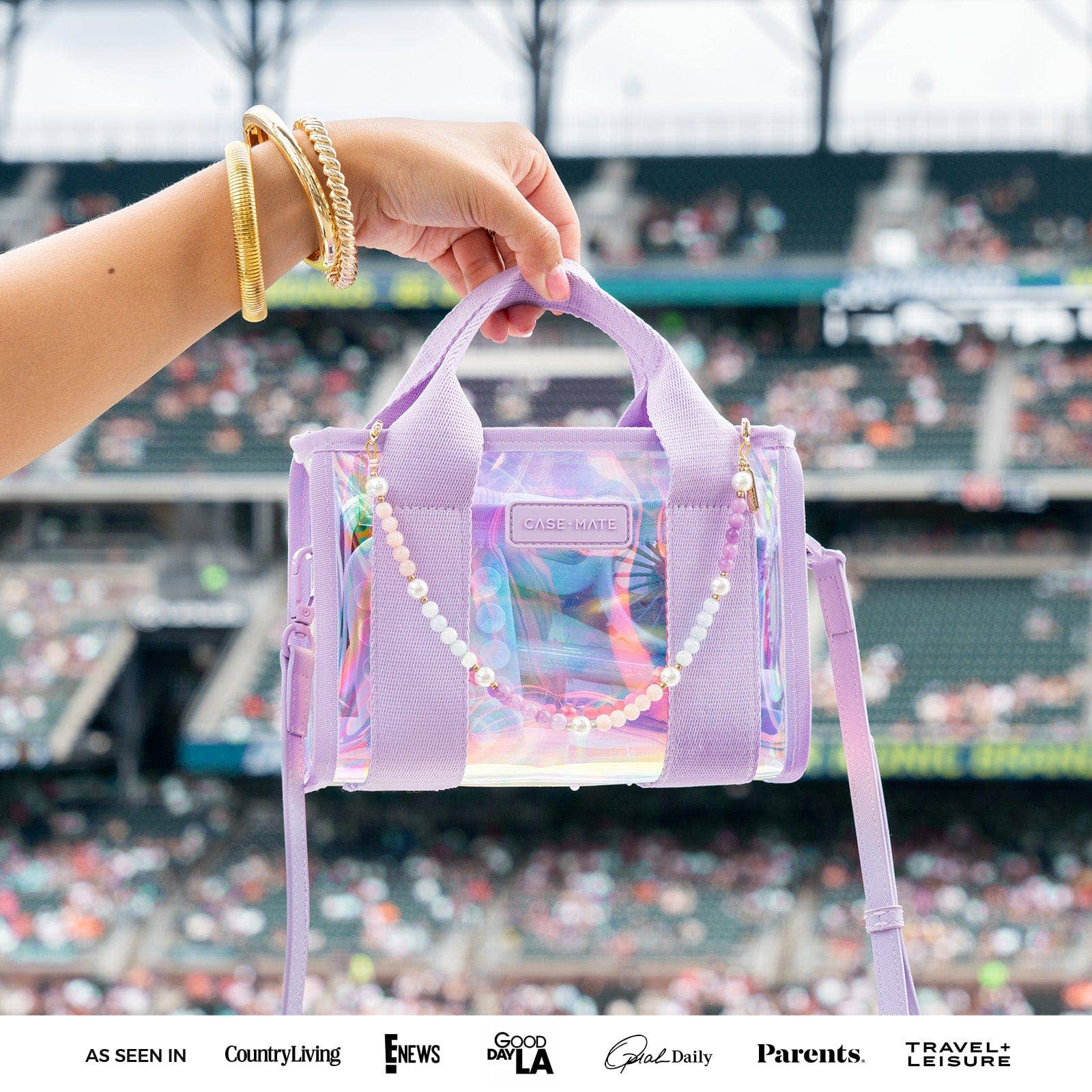 Hand holding a colorful transparent handbag with a stadium in the background