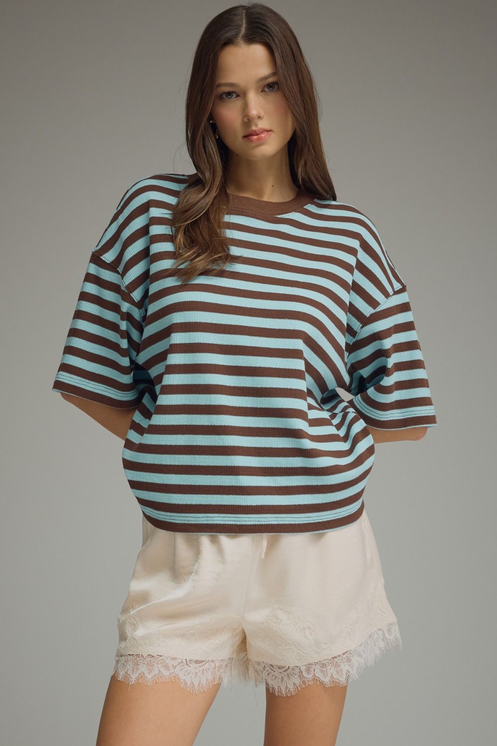 Woman wearing a striped shirt and shorts on a gray background