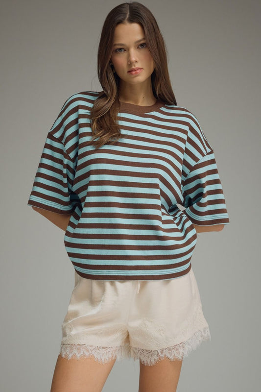 Woman wearing a striped shirt and shorts on a gray background