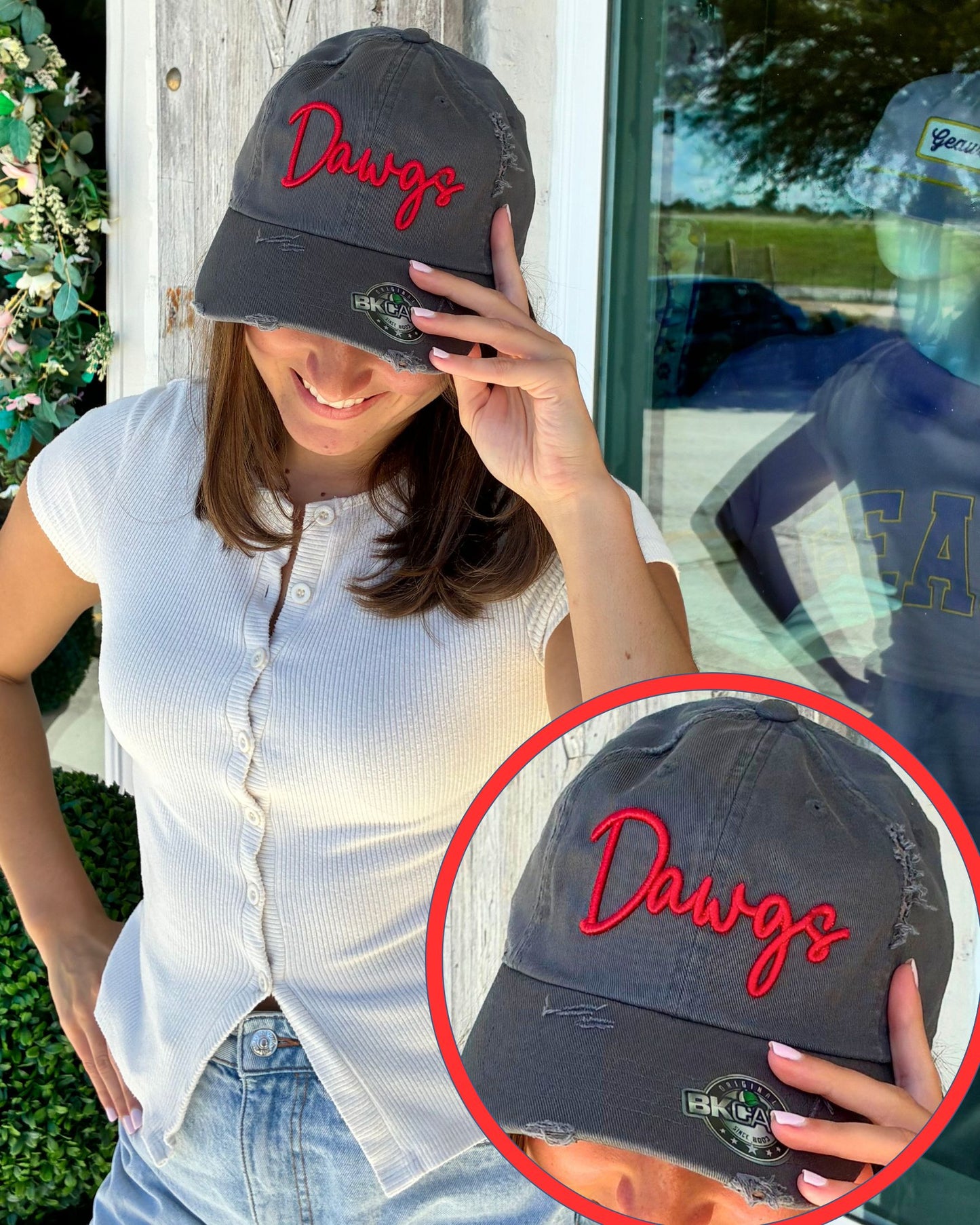A woman wearing a dark gray baseball cap with red embroidered script reading 'Dawgs' and a small circular patch on the brim. A circular inset shows a close-up of the cap with the same embroidery and patch.