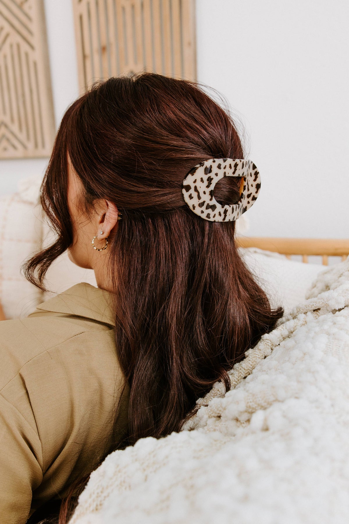 Woman relaxing on a sofa wearing a blonde tortoise flat clip in a twist