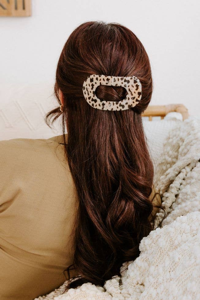 Large blonde tortoise flat clip holding a half-up style on long brown hair
