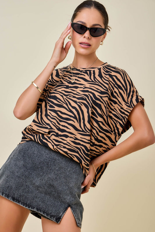 Woman wearing a tiger or zebra  print top and denim skirt on a beige background