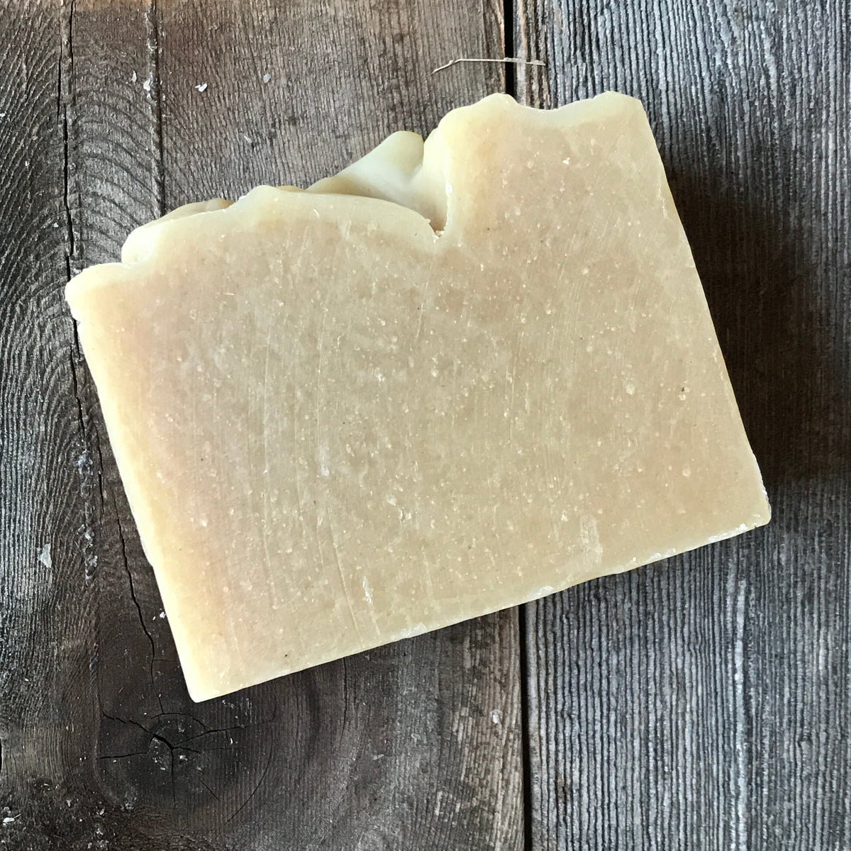 Unwrapped creamy Cucumber Mint bar soap on wood