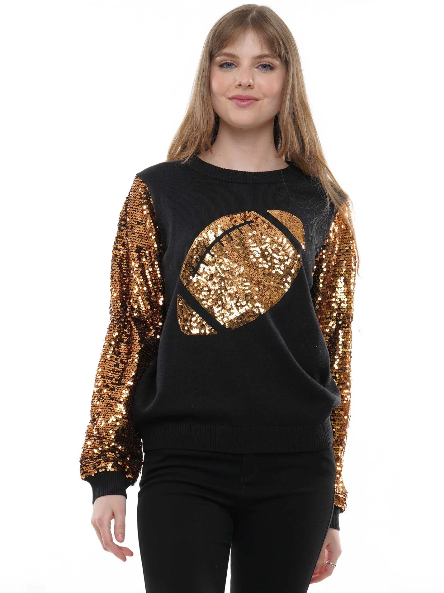 A woman modeling a black long-sleeve sequined sweatshirt with a large gold football graphic on the front and gold sequined sleeves, paired with black pants against a plain white background.