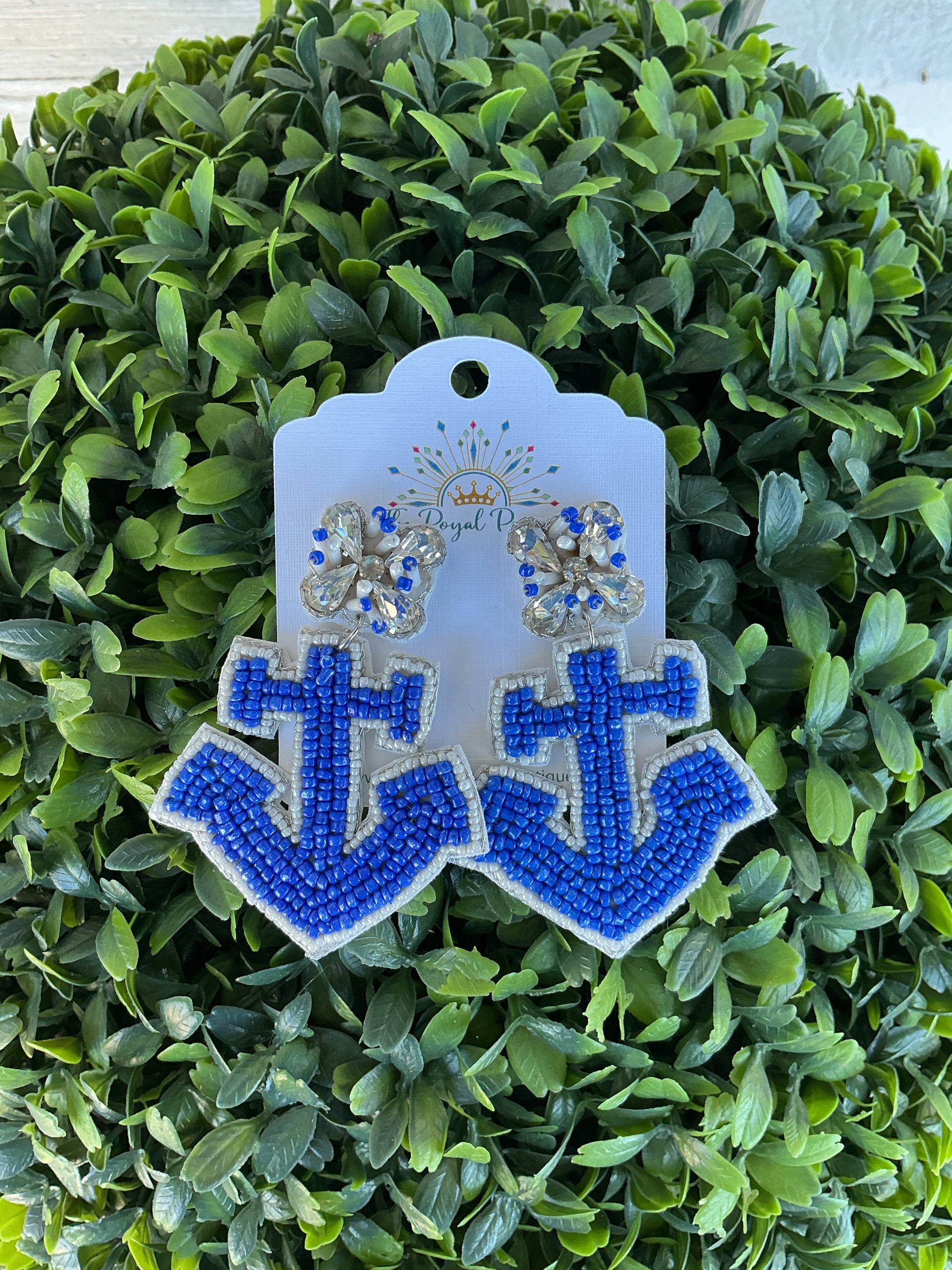 Beaded anchor earrings on a green plant background 