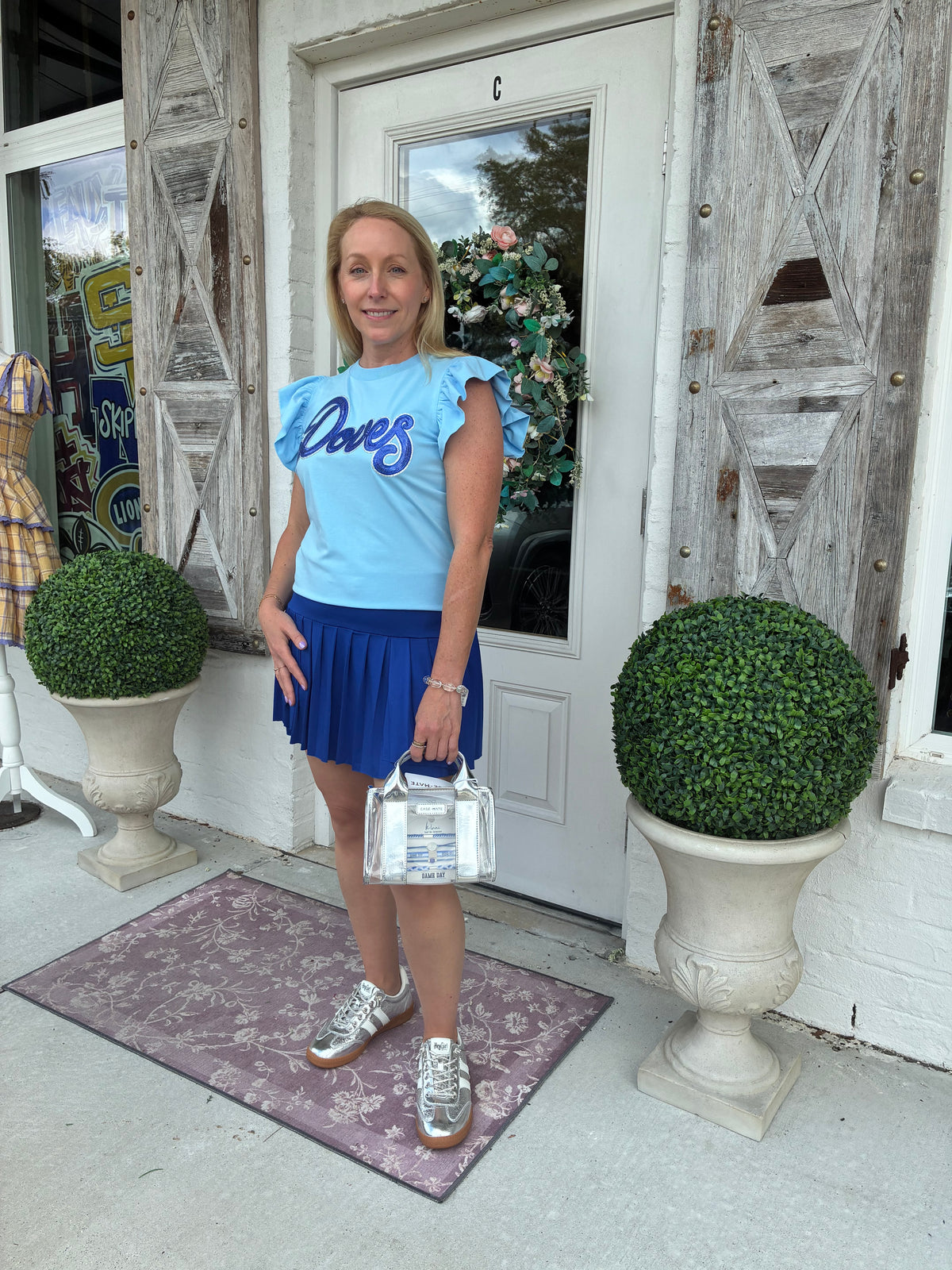women wearing a light blue top with ruffle sleeves with a Royal Blue and Silver Doves Sequin Patch 