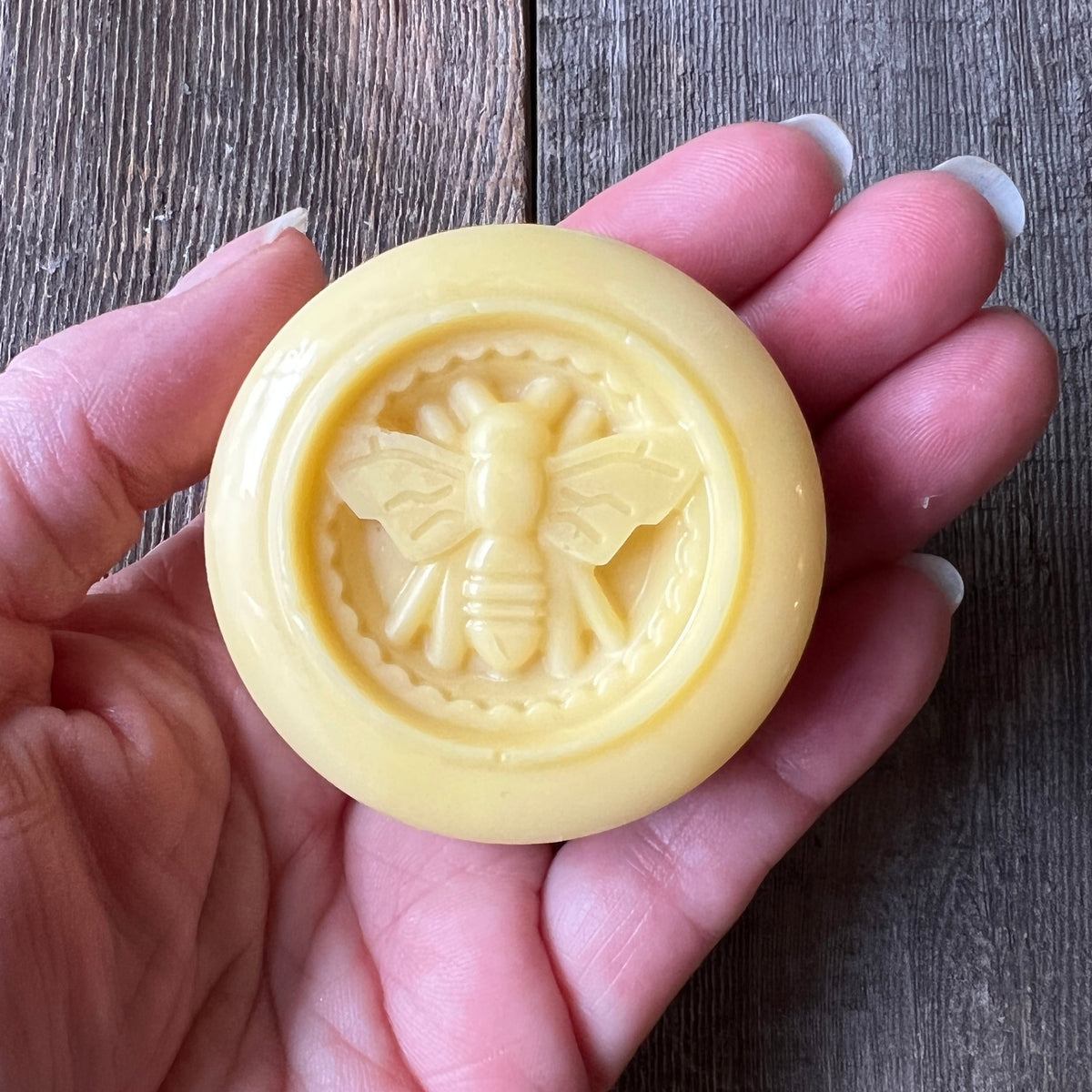 Hand holding a golden honeybee lotion bar