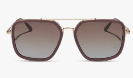 A pair of aviator-style sunglasses with a dusty purple translucent frame, gold metal temples, and gradient cocoa and light blue lenses, shown against a plain white background.
