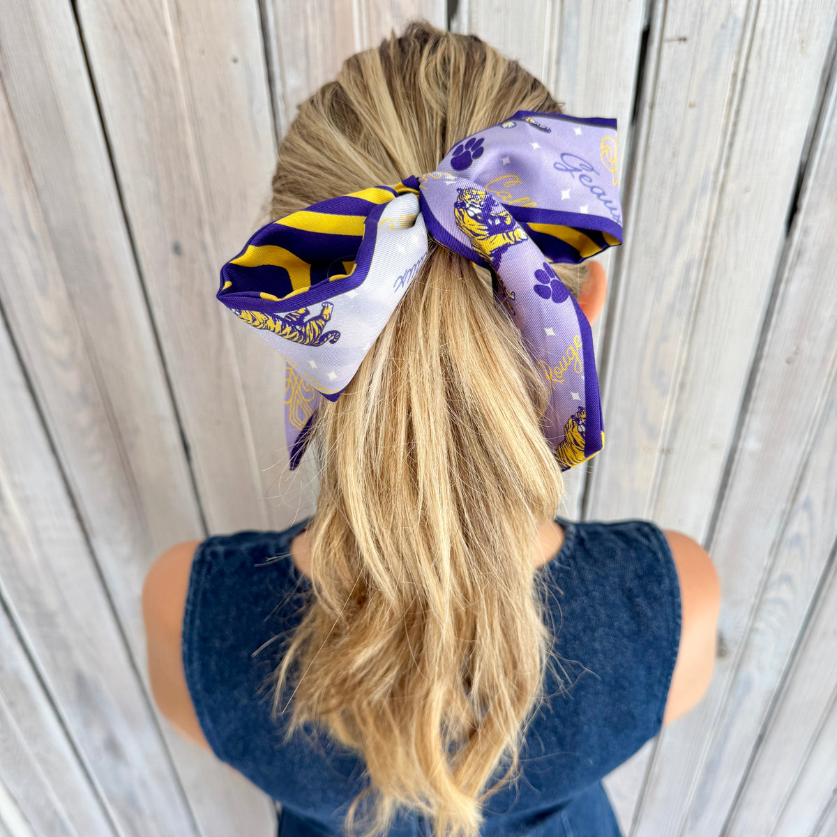 Purple and gold silk twilly tied in a bow on a ponytail