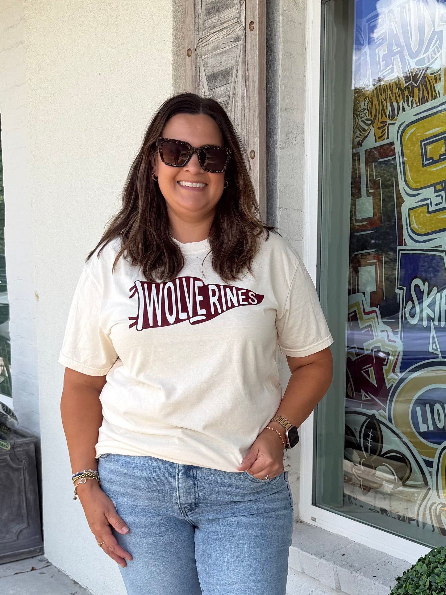 a woman wearing an ivory shirt with a maroon pennant flag with the word Wolverines inside 