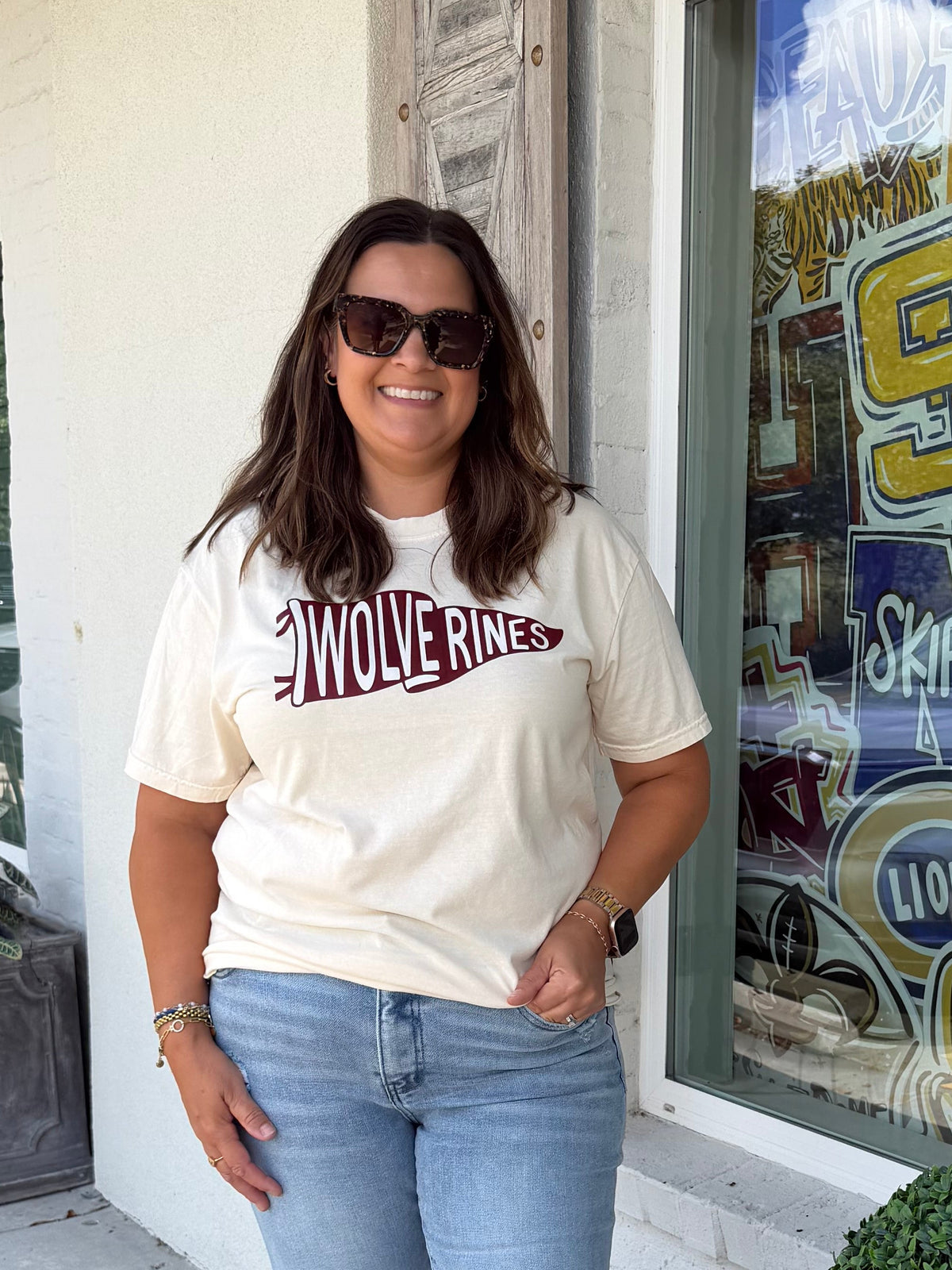 a woman wearing an ivory shirt with a maroon pennant flag with the word Wolverines inside 